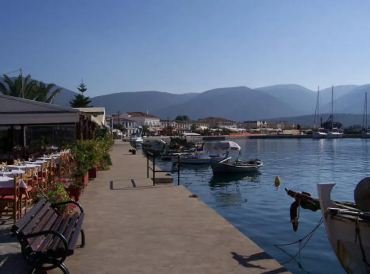 Coastal harbor promenade in Sami near Melissani Cave with cafes, docked boats, and mountain views